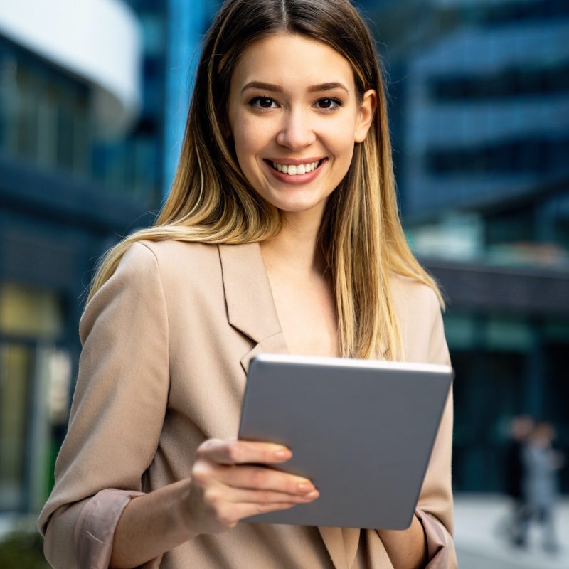 successful-businesswoman-using-a-digital-tablet-while-standing-in-front-of-business-building.jpg