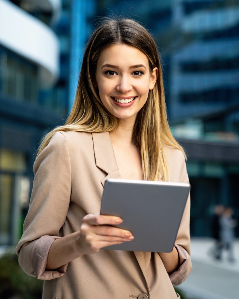 successful-businesswoman-using-a-digital-tablet-while-standing-in-front-of-business-building.jpg